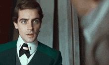 a man in a green suit and tie has a button on his collar that says ' a ' on it