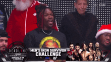 a man in a santa hat stands in front of a deadline men 's iron survivor challenge banner