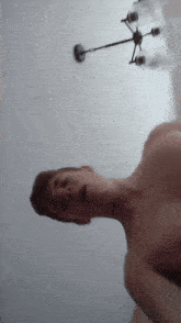 a man without a shirt is standing in front of a light fixture