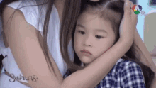 a woman is holding a little girl in her arms who is looking at the camera .