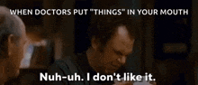 a man in a black shirt is talking to another man in a dark room .