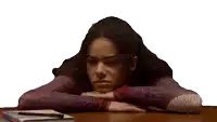 a woman rests her head on her hands at a table