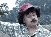 a man with a red hat and a mustache says xo drogrado in a foreign language