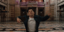 a man in a black jacket is dancing in front of a building with purple lights on