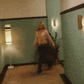 a woman walking down a hallway next to a plant and a lamp