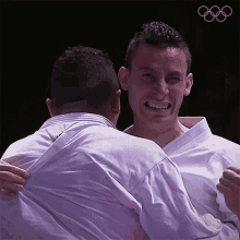 a man in a white shirt is hugging another man in a purple shirt