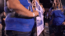 a man in a blue shirt is holding a sign that says ' brian ' on it .