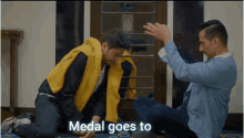 a man in a yellow jacket is kneeling down next to another man with the words medal goes to on the bottom