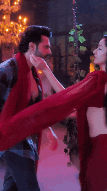 a man and woman are dancing together and the woman is wearing a red dress