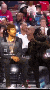 a man wearing a gas mask sits in a crowd of people at a basketball game