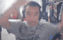 a man wearing headphones and a reebok shirt is dancing in front of a camera .