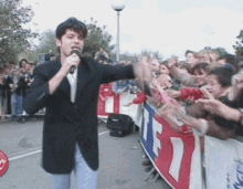 a man singing into a microphone in front of a crowd with a banner that says tf7