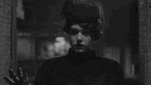 a black and white photo of a man in a top hat walking down a dark alleyway .
