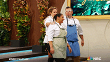 a group of people standing in front of a wall with nbc written on the bottom