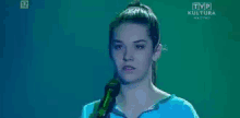 a woman singing into a microphone with tvp kultura written on the bottom