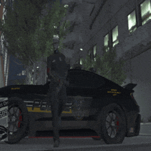 a police officer stands in front of a black car with the word police on the side