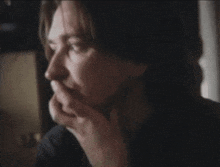 a woman covering her mouth with her hand while looking out a window