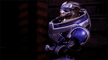 a video game character is wearing a blue and silver armor and looking at the camera .