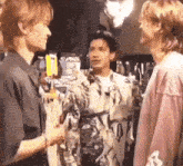 three young men are standing next to each other in a room .