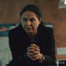 a woman sitting with her hands folded in front of a netflix sign
