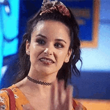 a woman wearing a choker and a ponytail is waving her hand .