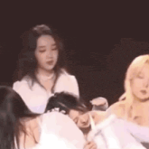 a group of women are sitting in a circle on a stage in a dark room .