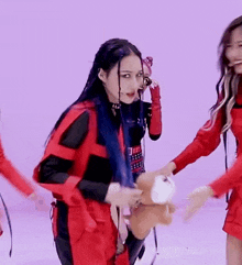 a woman in a red and black outfit is holding a stuffed animal