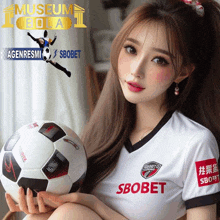 a woman holding a soccer ball in front of an ad for sbobet