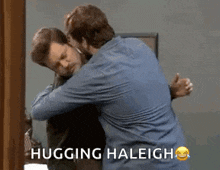 two men hugging each other in front of a mirror with the words hugging haleigh written on the bottom .