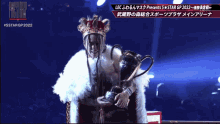 a man in a crown is holding a trophy in front of a sign that says 5stargp2022