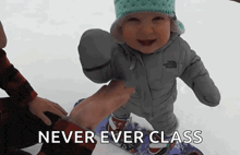 a baby wearing a north face jacket is being held by a person in the snow