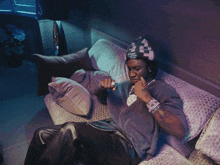 a man sitting on a couch with his hands outstretched and a hat on that says ' a ' on it