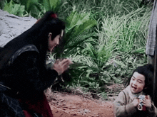a man and a little girl are standing next to each other in a forest .