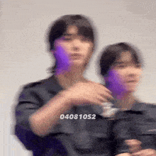 a blurry picture of two people standing next to each other with a purple light behind them .