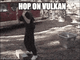a man is standing on a box in front of a red van and a trash can .