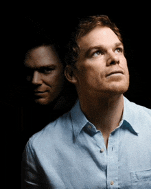 a man in a blue shirt is looking up with another man behind him