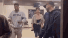 a group of people are standing in a room and talking .