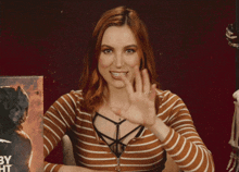 a woman in a striped shirt is holding a book that says by night