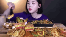 a woman in a blue shirt is eating a lot of food