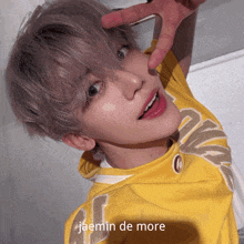 a young man wearing a yellow shirt with the name jaemin de more on the bottom