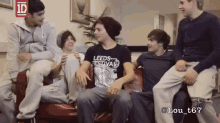 a group of young men are sitting on a couch and one of them is wearing a leeds festival t-shirt