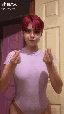 a girl with red hair is wearing a purple bodysuit and making a heart with her hands