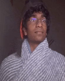 a young man wearing glasses and a striped sweater