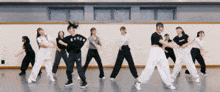 a group of women are dancing in a room and one of them is wearing a black shirt that says kncob on it