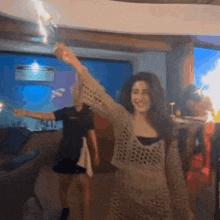 a woman is holding a bottle of champagne in her hand while dancing in a room .