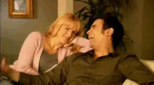 a man and a woman are sitting on a couch and the woman is touching the man 's face