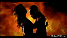 a man and a woman are dancing in front of a fire background .