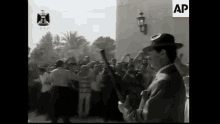 a man in a hat stands in front of a crowd of people with an ap logo on the bottom
