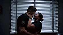 a man and a woman are kissing in front of a window