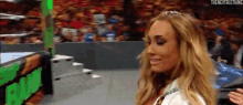 a woman is standing in front of a crowd in a wrestling ring wearing a tiara .